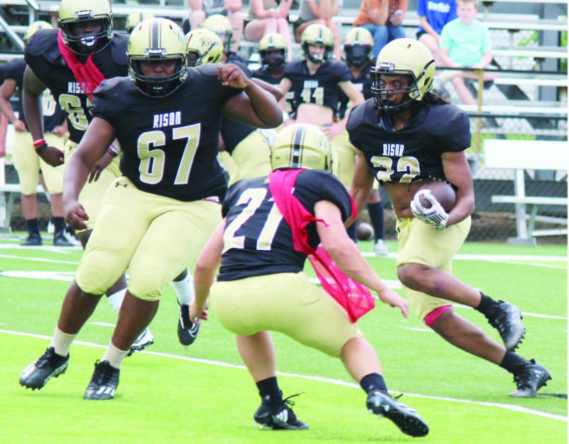 MAKING HIS MOVE -- 32 follows the block of TJ Markss (no.. 67) on defender Aaron Tilley (no. 21) during the Risonn Wildcats'' scrimmage last Thursday at George Walker Field of Champions. 32 hadd a nice scrimmage,, taking one pitch about 455 yards for aa touchdown. Risonn used threee quarterbackss with the first team offense and several players at running back.