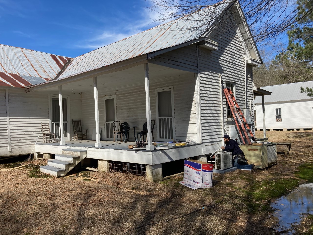 MODERN CONVENIENCES FOR A 19TH CENTURY HOME - Steve Salano of K&Z Electrical Solutions installs one of the "split" air conditioning/ heating units behind the McMurtrey House at the Pioneer Village in Rison Monday morning.