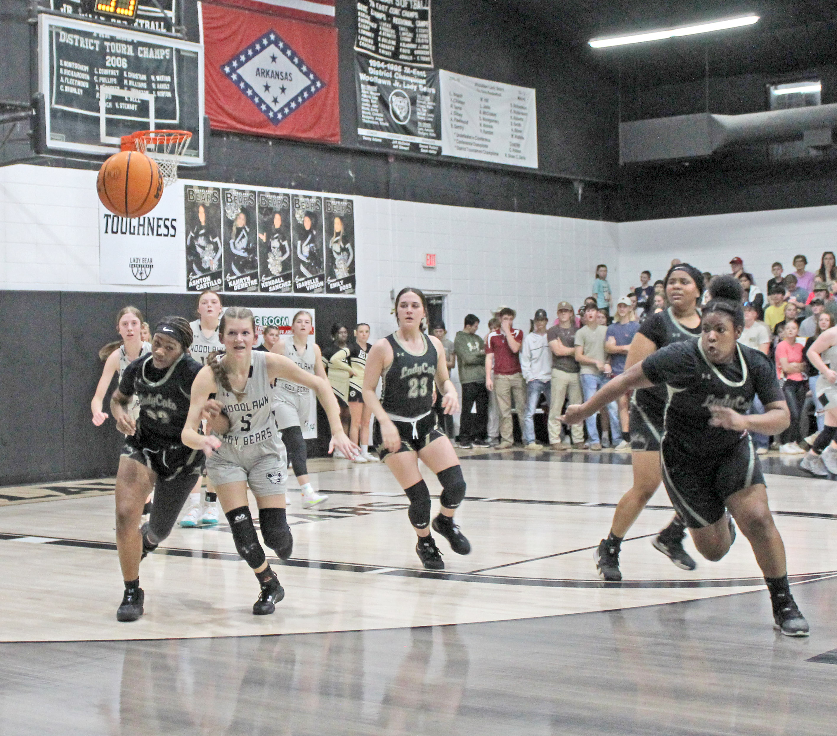 LOOSE BALL BATTLE - Rison's Carlese Johnson and Woodlawn's Kathryn Dixon (left) race for a loose ball during first half action of last Thursday's Cleveland County rivalry game inside a packed Woodlawn Gym. Also pictured for Rison (center to right) are Layne Potter (no. 23), Rerel Roshell and Chamira Crain.