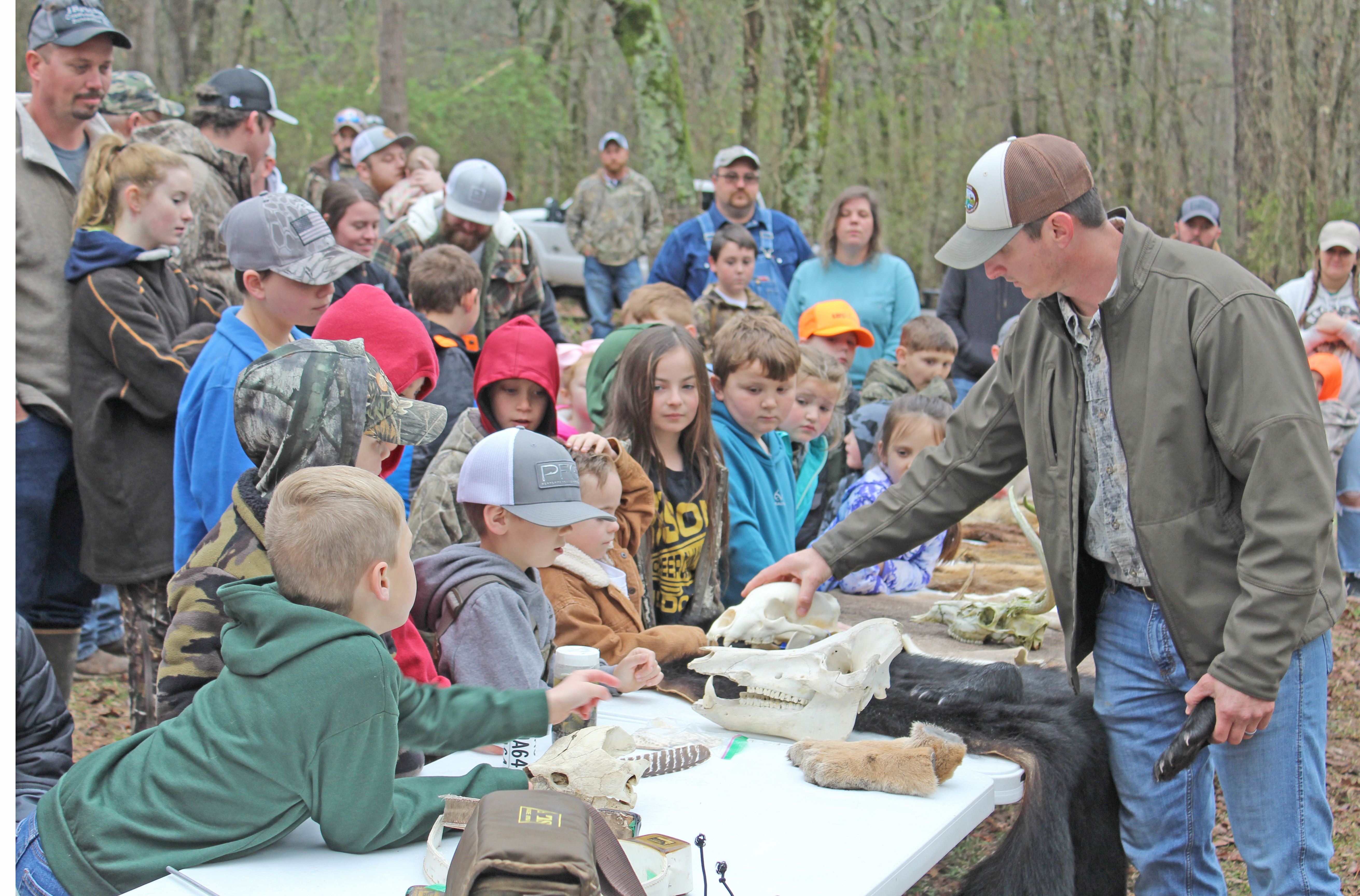 LEARNING ABOUT ARKANSAS WILDLIFE - Jeff Lawson, a wildlife biologist for the Arkansas Game & Fish Commission from Rison, shows a group of curious onlookers a bear skull during the Cleveland County Cutters & Strutters National Wild Turkey Federation Jakes Day event held at the old turkey farm off Mt. Elba Road south of Rison. More than 200 youth registered for the event as more than an estimated $10,000 in prizes was given away.