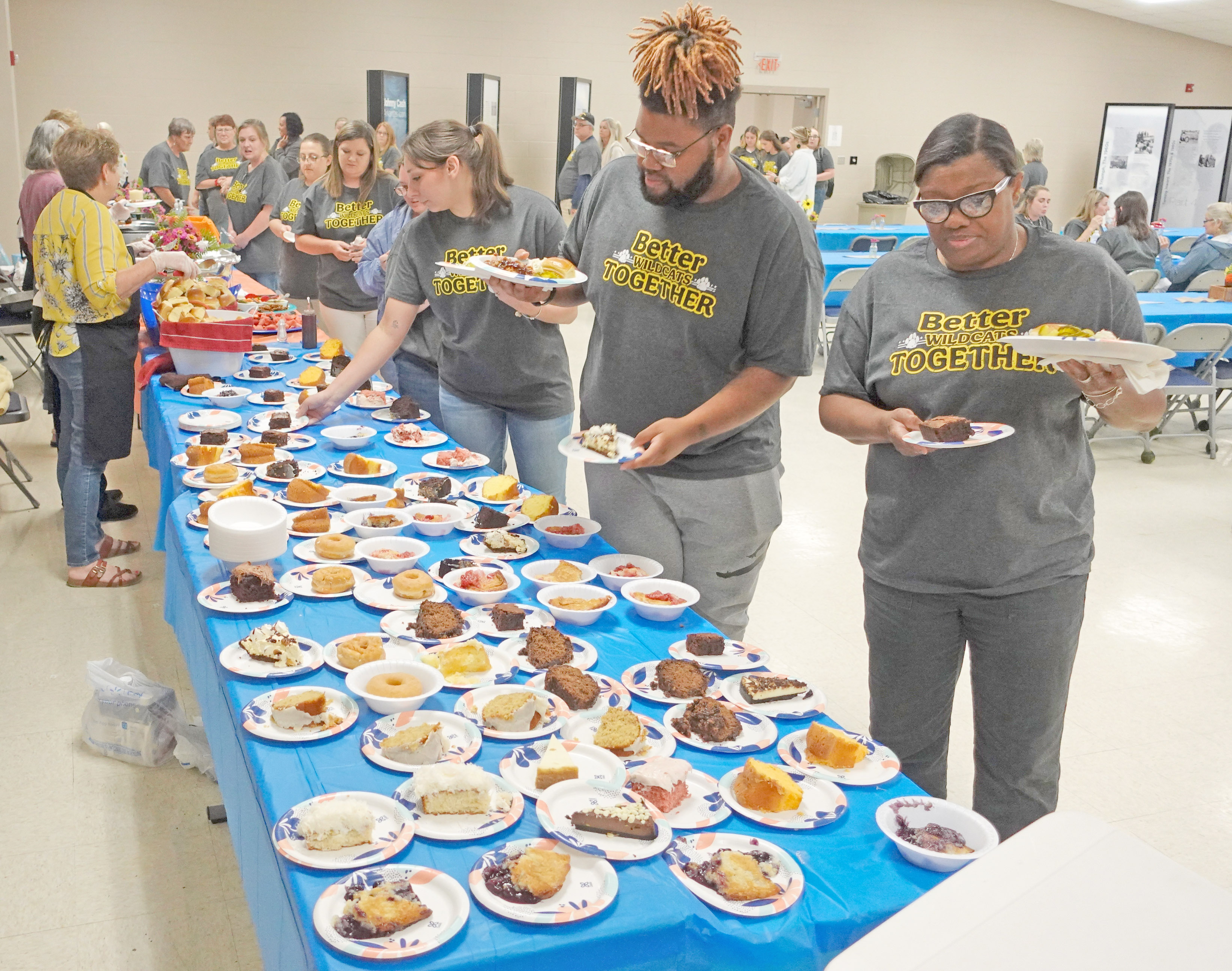 Dionte Langford (second from right) and Willie Bea Brandon (right) check out the homemade desserts that were part of a pulled pork meal that Jo Wegner of Kingsland organized for all Cleveland County School District staff, including those who work for Cleveland County Head Start program. Nearly 150 gathered inside the Kingsland School auditorium for a lunch that included door prizes provided by Rison businesses.