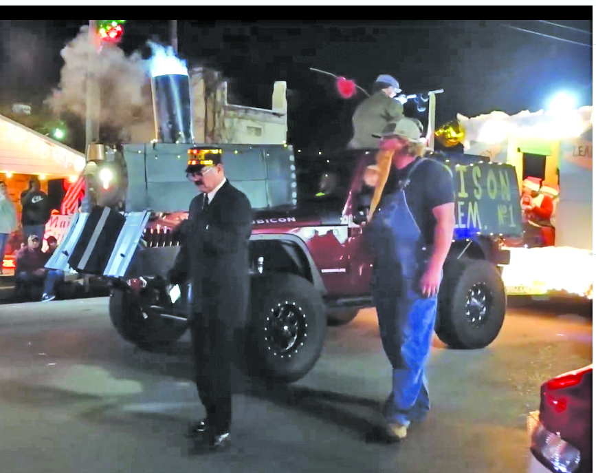 The conductor checks his watch as smoke rises from the smoke stack of the locomotive pulling a passenger train car in Rison Elementary's Polar Express float, judged the winner for this year's parade.
