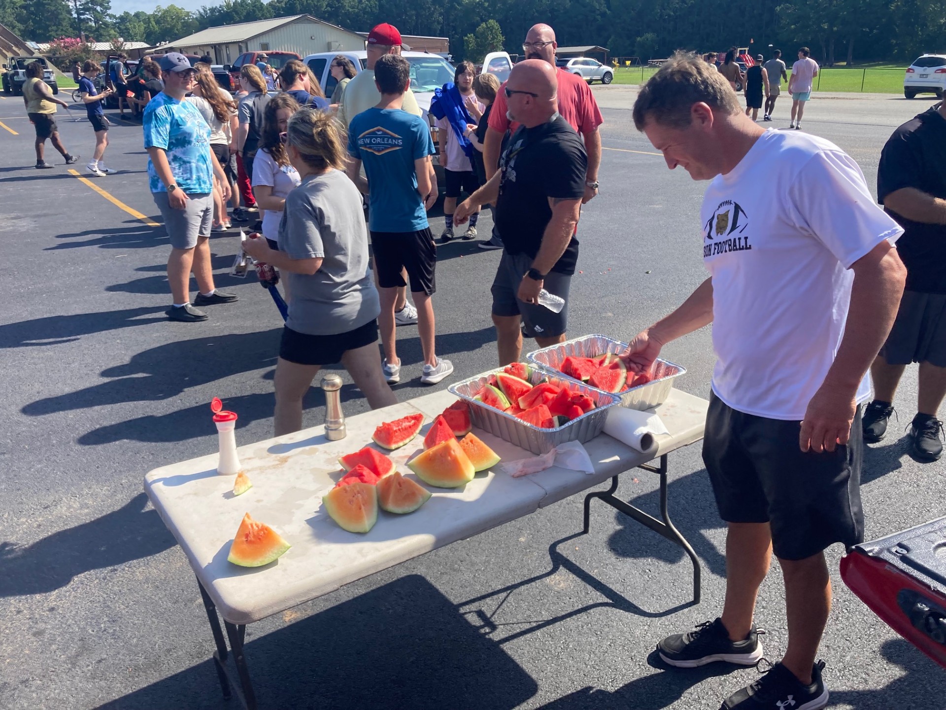 MELON TIME FOR THE WILDCATS - Rison baseball/assistant football coach Chad Cope reaches for a piece of watermelon in a post-practice treat furnished by John Varnell and Donnie Wilson. This is the second consecutive year that the Wildcats have been treated to watermelon after summer workouts. All the Rison High School athletic teams as well as the band and cheer leaders were invited to attend. 