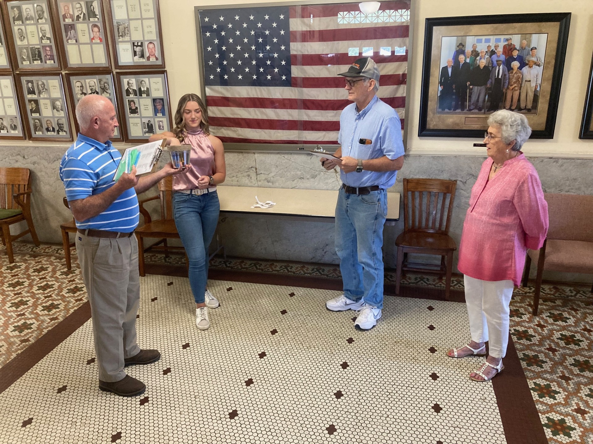 Cleveland County Election Coordinator Billy Bowlin (left) holds a bucket while Woodlawn High School senior Sarah Beth Melhorn (second from left) draws names to determine the order that the presidential candidates will appear on the 2024 general election ballot in Cleveland County.