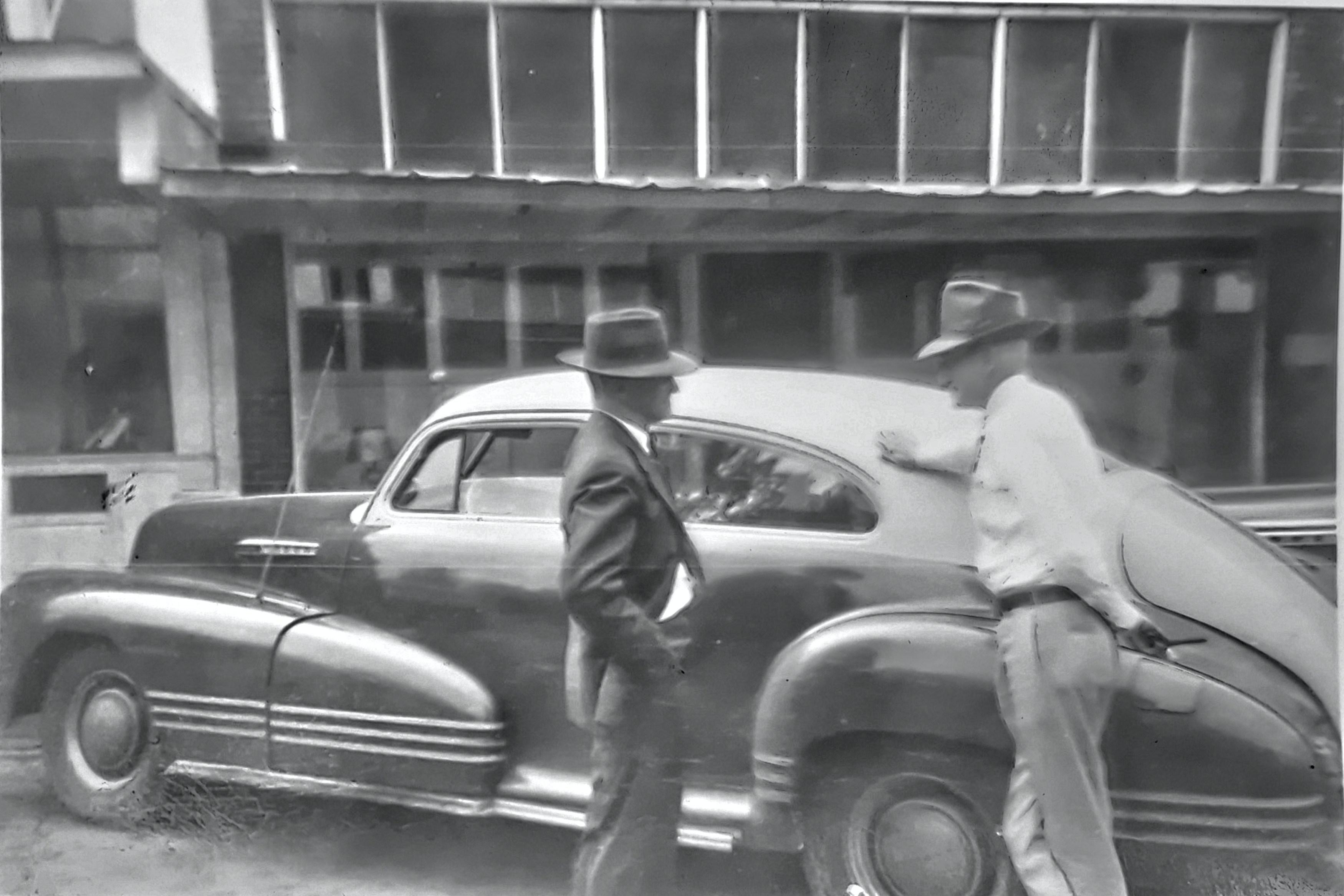 GLIMPSES  FROM  THE  PAST - This is a Rison Main Street glimpse from another time, as we see a couple of gentlemen having a discussion next to a car - possibly a late 1940's Chevrolet Fleetline, or possibly a Pontiac Torpedo (please, let us know if you can identify the automobile). We feel certain this photo was made in the second block, but we can't be sure about which buildings are seen in the background. The fellow at right we believe we know, evidence given away by what looks to be a cigar in his hand. 