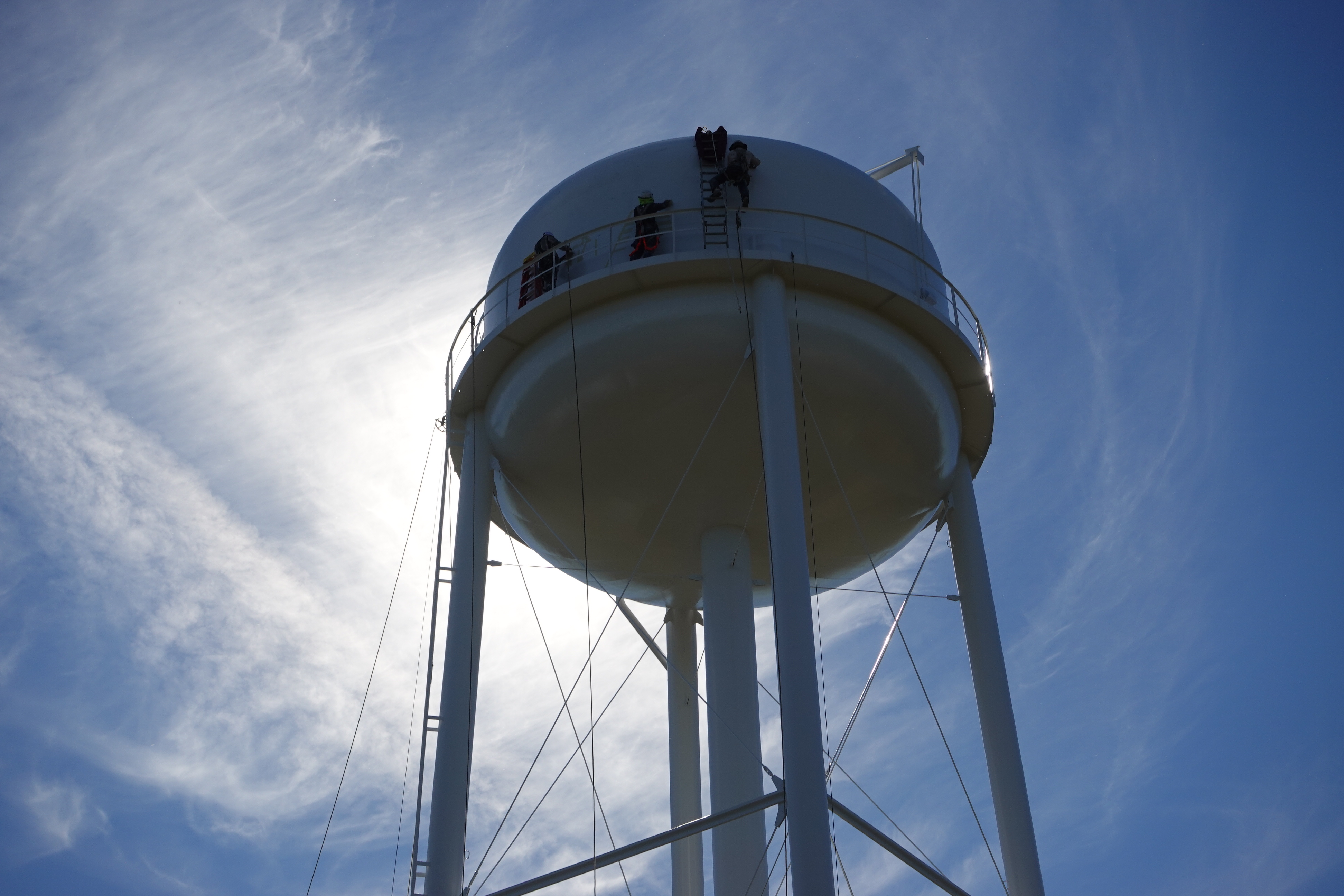 WATER TANK RENOVATION NEARLY COMPLETED - Workers on a scaffold apply the final coat of paint to the Rison water tower at Veterans Park Tuesday while another crew at the top begins to mask off the tank for a mural scene that will be painted later this week. A member of the work crew said the project could be completed by the end of the week, weather permitting. Rison was awarded at $1.62 million grant in 2023 to refurbish both of its water tanks. The “tin man” water tank next to the courthouse was completed 