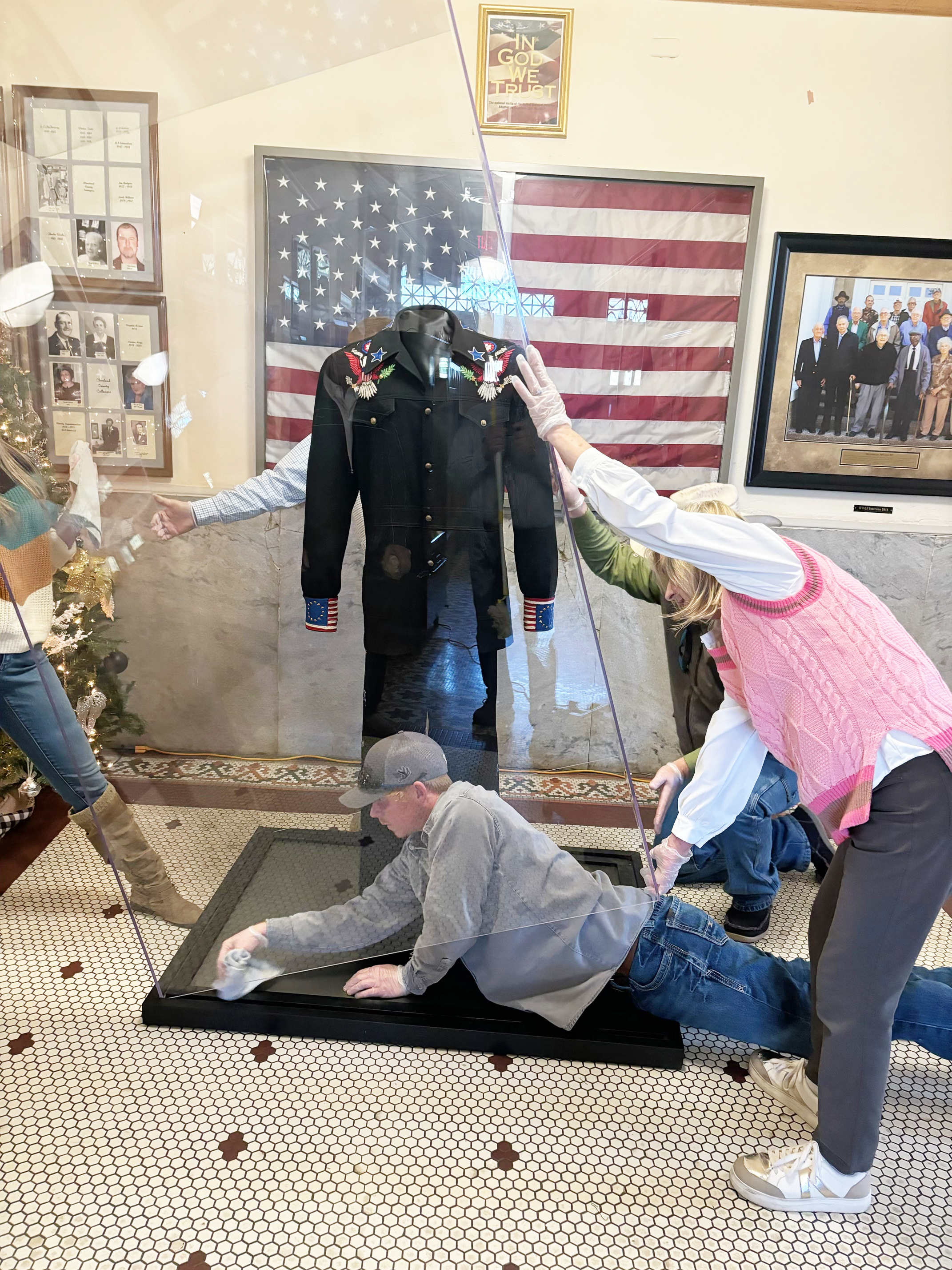 FINISHING TOUCHES ON NEW DISPLAY CASE - One of the four crew members from Watson Chapel Picture Frame installing the new display case for the suit that Johnny Cash wore during his 1976 Bicentennial Concert at the Rison High School football stadium wipes up the inside of the dust-proof case before dropping it down. After being displayed for a year at the Rock and Roll Hall of Fame in Cleveland, Ohio, and then the past few years at the Johnny Cash boyhood in Dyess, Ark., the suit is now home in its permanent.