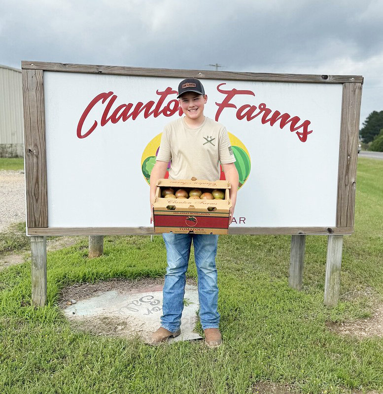 First box of tomatoes - Westin Clanton holds the first box of tomatoes — a batch of Cherokee Purples — delivered to the Bradley County Extension Office on May 19. Westin is the son of Randy Clanton, Jr., and Skye Clanton, owners of Clanton Farms in Hermitage, Arkansas. (Image courtesy John Gavin)