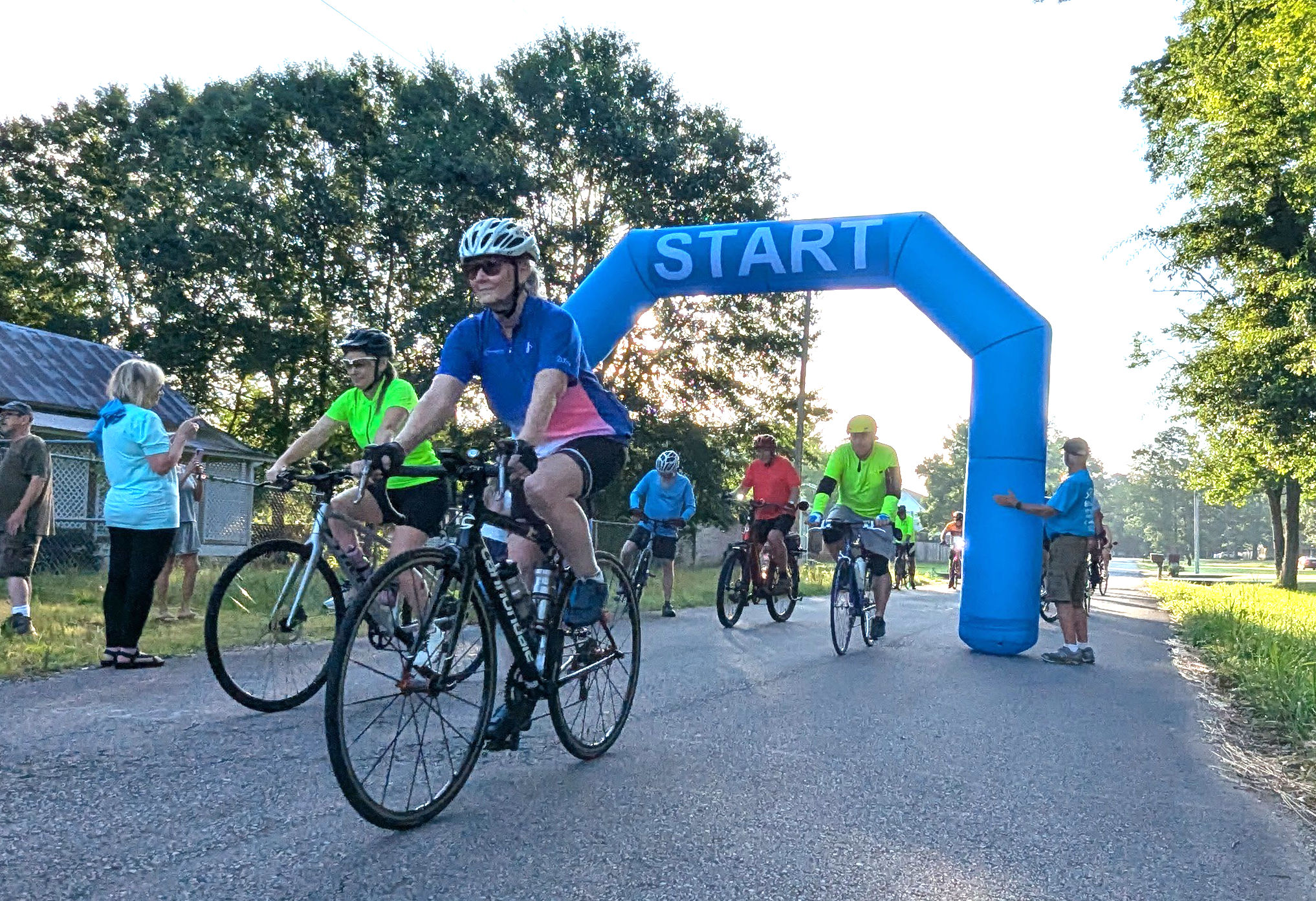 RIDERS DEPART - Riders roll out from beneath the inflatable start-finish archway set up outside the Pioneer Village at Rison for the Third Annual Cruisin’ Cleveland County bike ride held early Saturday morning. More than 20 riders from across the state took to the roads to ride routes that went as far as 65 miles. (Photo by Douglas Boultinghouse)