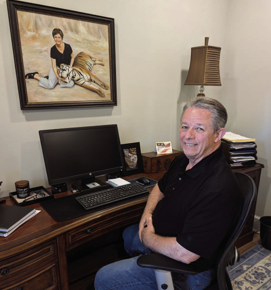 Jim Houston at his desk beneath a portrait of his wife, Brenda, with a tiger inside tiger sanctuary outside Bangkok, Thailand. Houston spent several years working in Southeast Asia