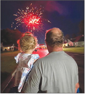 Ava Stell watches the fireworks at the Green House Cottages of Southern Hills with her grandfather, Ricky Farrer, on Independence Day (Photo by Libby Stell). 