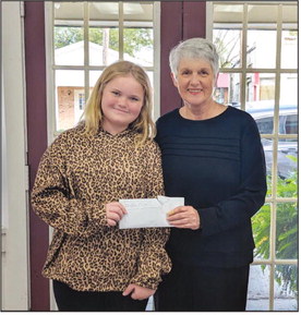 RAULS RAISES OVER $2,000 FOR CHARITY - Jayci Rauls (left) is pictured with Cleveland County Cares organizer Melinda McKnight (right) making a donation to the charity which provides Christmas to families in need. Rauls started her donation efforts with a $50 spelling bee prize that quickly gained traction in the community.