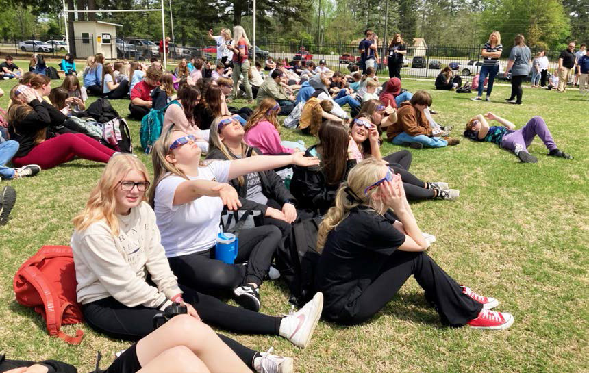 Students at Woodlawn High School kick back on the football field to take in the eclipse Monday afternoon.