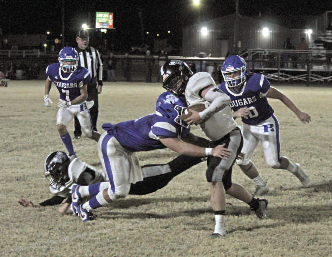 TOUGH GOING - Woodlawn junior fullback Ethan Olvier (center) tr ies to elude the tackle of Rector senior linebacker Drew Henderson during Friday night's first-round playoff game at Cougar Stadium in Rector. Henderson was part of a Cougar linebacker corps that Bears Coach Zach Meyer said is the best he has seen in two years. Once fumbles and other misques were figured in, Woodlawn finished the game with just 67 yards rushing on 36 carries, the Bears' lowest output of the season.
