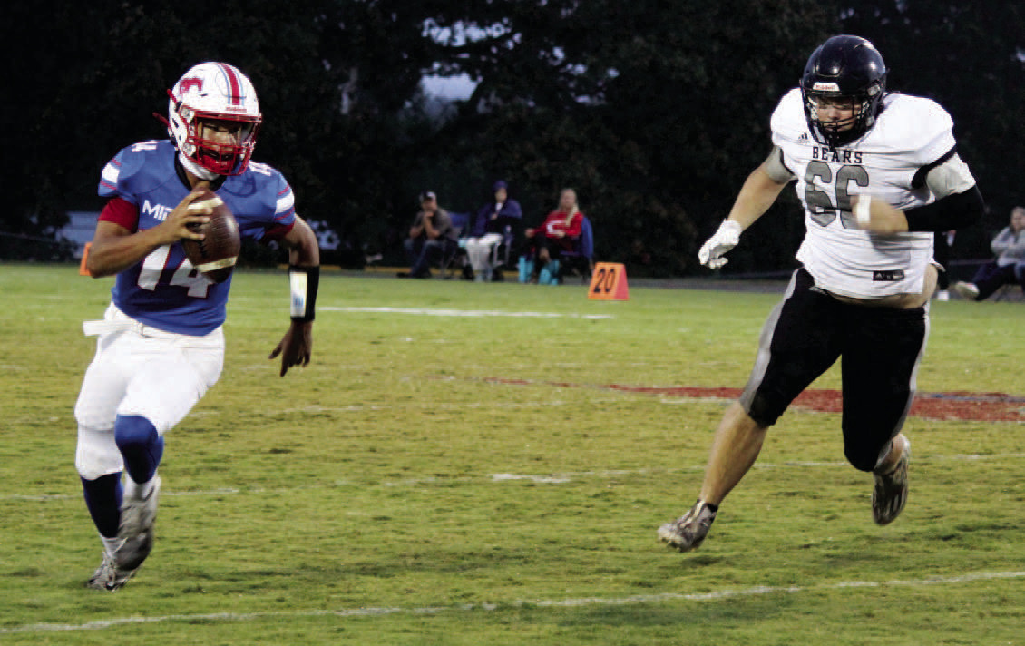BIG NIGHT FOR CAMPBELL - Woodlawn defensive lineman Dakota Campbell (right) pursues Midland quarterback Chase Rascoe during first half action. Campbell had eight tackleswith seven of those going for losses. He also had a fumble recovery and was in on four third down stops.