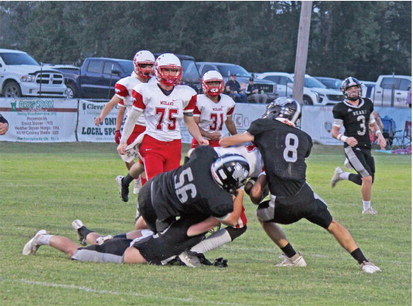 NO REST FOR RASCOE - Midland sophomore quarterback Chase Rascoe is buried near the line of scrimmage by Woodlawn's Ethan Adair (bottom), Steven Adair (no. 56) and Aidan Johnson (no. 8) during first half action. The Bears defense turned in another solid effort, registering several tackles at or behind the line of scrimmmage. Woodlawn defensive coordinator Alan Neill noted that the starting defense has give up 12 points through the first two games of the season.