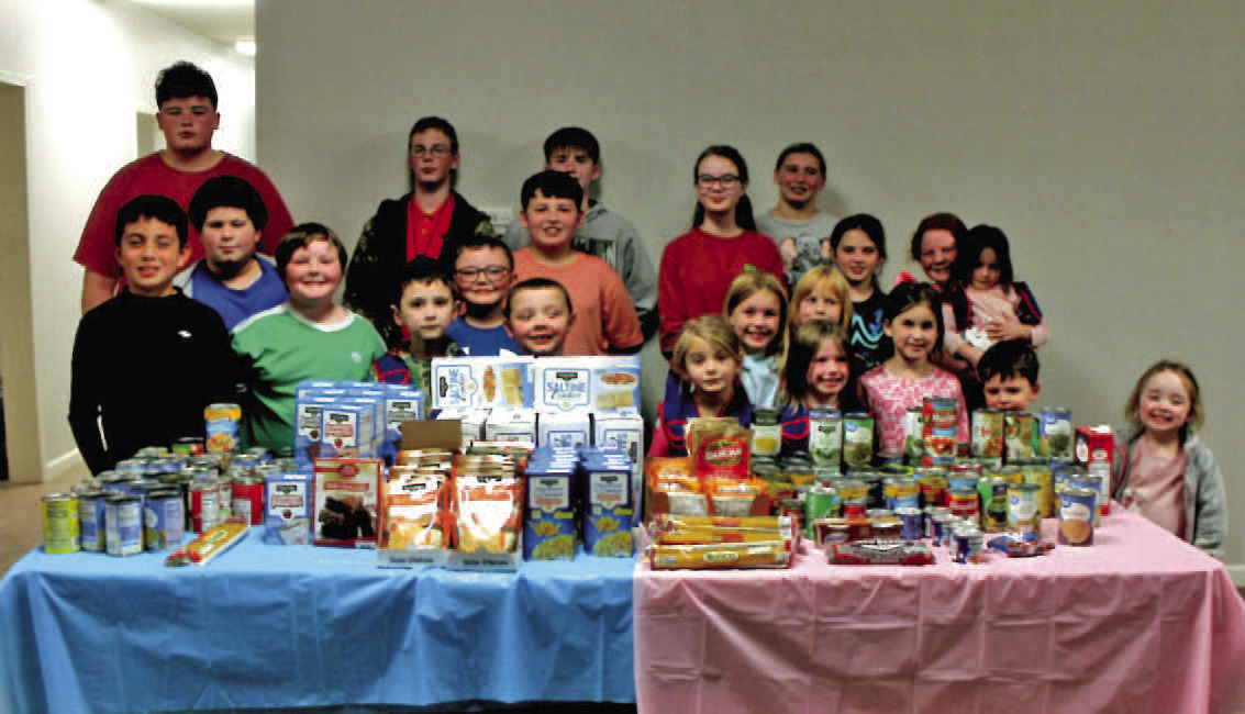 MACEDONIA MBC AWANA FOOD DRIVE - Members of the Awana program at Macedonia Missionary Baptist Church near Rison pose with the collection from their "boys versus girls" food drive held throughout the month of November. Debbie Leopard, one of the Awana leaders at Macedonia, said the food will be distributed through the church's food pantry beginning this month.