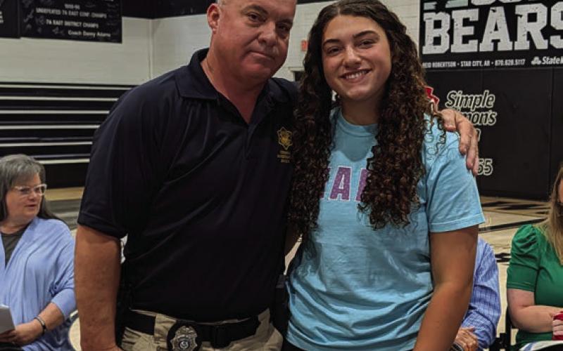 State Trooper Randy Rauls presents the Arkansas State Police Randy and Betty Hedge Spouses' Auxiliary Scholarship to Laci Rauls