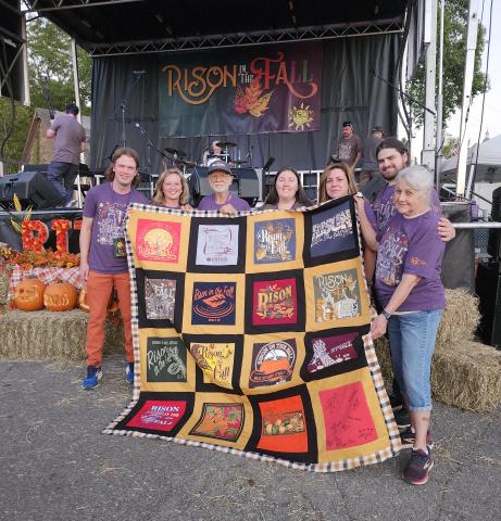 FESTIVAL HONORS FOUNDER - Rison Shine’s core festival-planning team surprised founder Roy Phillips with a special quilt made from t-shirts from previous years. Pictured left to right: Douglas Boultinghouse, Stacy Walz, Roy Phillips, Kristy Strother, Celeste Beatty, Austin Compton and Malinda Berry. Not pictured: Keden Shrum. (Photo by Tara Neff)