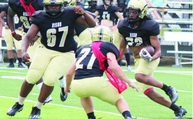 MAKING HIS MOVE -- 32 follows the block of TJ Markss (no.. 67) on defender Aaron Tilley (no. 21) during the Risonn Wildcats'' scrimmage last Thursday at George Walker Field of Champions. 32 hadd a nice scrimmage,, taking one pitch about 455 yards for aa touchdown. Risonn used threee quarterbackss with the first team offense and several players at running back.