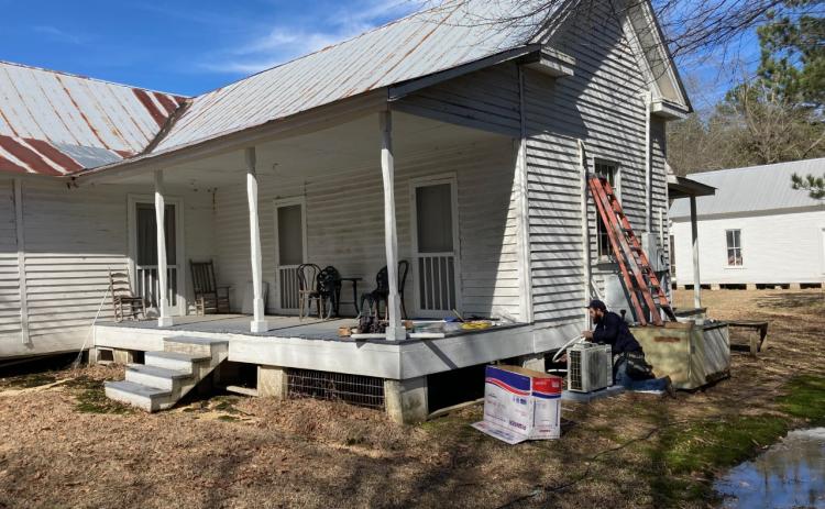 MODERN CONVENIENCES FOR A 19TH CENTURY HOME - Steve Salano of K&Z Electrical Solutions installs one of the "split" air conditioning/ heating units behind the McMurtrey House at the Pioneer Village in Rison Monday morning.