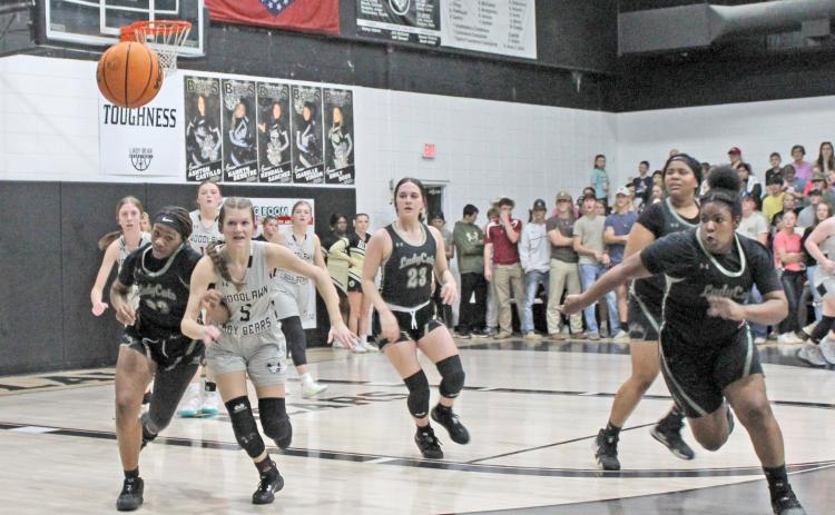 LOOSE BALL BATTLE - Rison's Carlese Johnson and Woodlawn's Kathryn Dixon (left) race for a loose ball during first half action of last Thursday's Cleveland County rivalry game inside a packed Woodlawn Gym. Also pictured for Rison (center to right) are Layne Potter (no. 23), Rerel Roshell and Chamira Crain.