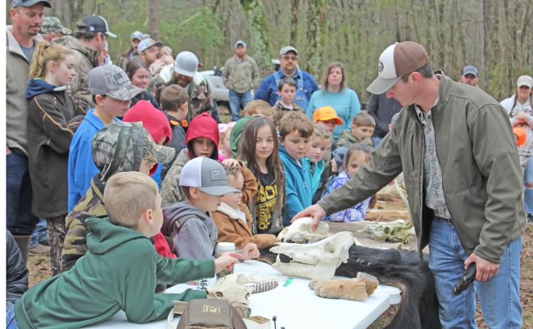 LEARNING ABOUT ARKANSAS WILDLIFE - Jeff Lawson, a wildlife biologist for the Arkansas Game & Fish Commission from Rison, shows a group of curious onlookers a bear skull during the Cleveland County Cutters & Strutters National Wild Turkey Federation Jakes Day event held at the old turkey farm off Mt. Elba Road south of Rison. More than 200 youth registered for the event as more than an estimated $10,000 in prizes was given away.