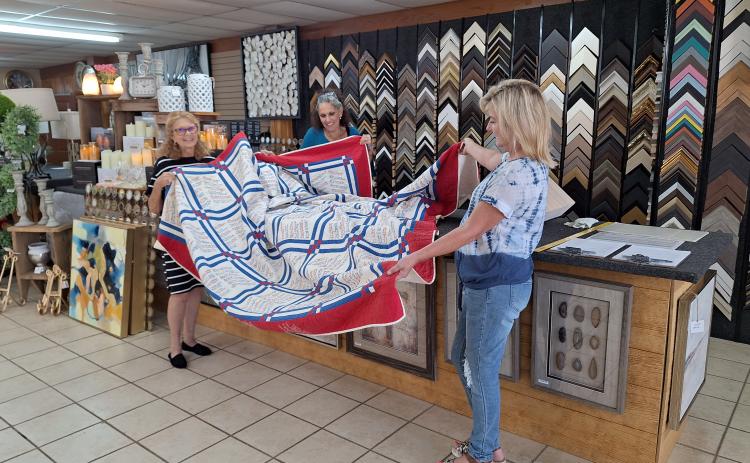 Karen Bell Fox with the Watson Chapel Picture Frame staff preparing the quilt for framing