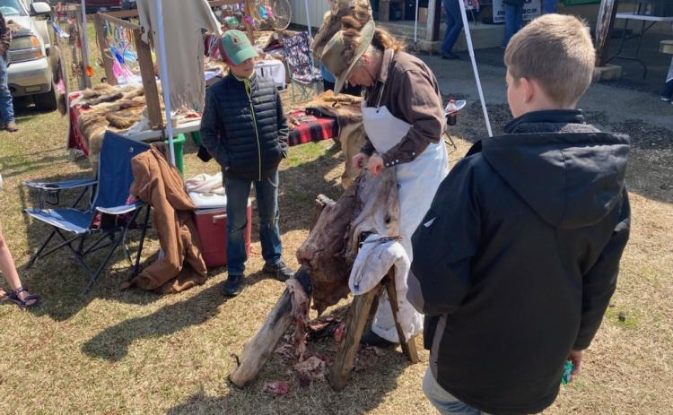 Shona Jordan, a taxidermist/hide tanner from Pike County, demonstrates to how to skin a hide to a couple of young attendees at the Arkansas Homesteading Conference Saturday at the Cleveland County Fairgrounds in Rison.