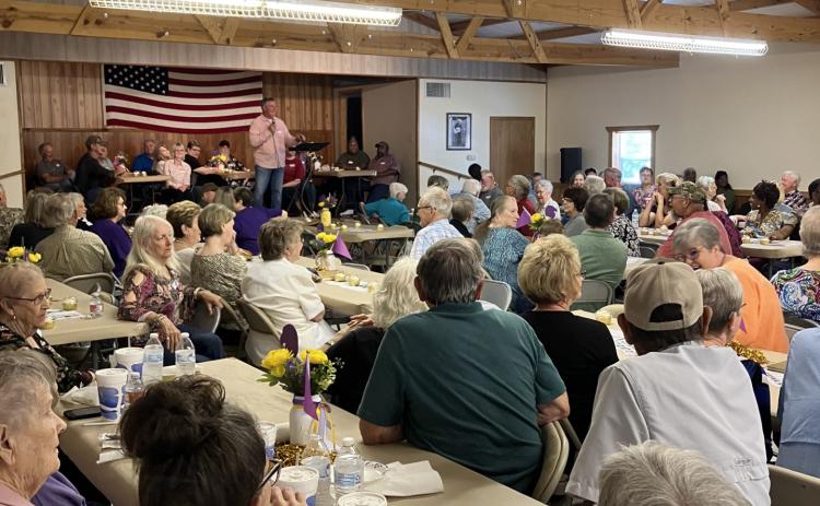Roger McClellan (standing on stage) welcomes visitors to the New Edinburg All-School Reunion held this past Saturday, April 27, at the New Edinburg Community Center.