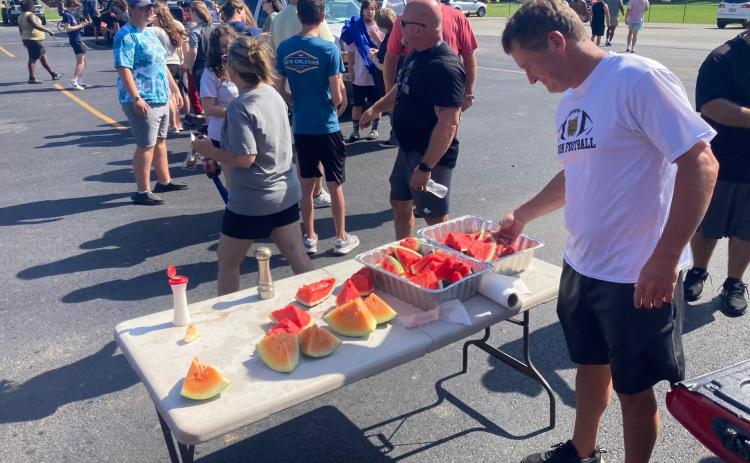 MELON TIME FOR THE WILDCATS - Rison baseball/assistant football coach Chad Cope reaches for a piece of watermelon in a post-practice treat furnished by John Varnell and Donnie Wilson. This is the second consecutive year that the Wildcats have been treated to watermelon after summer workouts. All the Rison High School athletic teams as well as the band and cheer leaders were invited to attend.