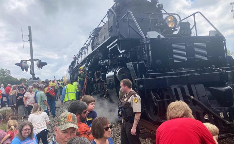 SERVICING BIG BOY NO. 4014 - Spectators engulf Union Pacific's Big Boy No. 4014, the world's largest operating team engine, when it made a "whistle stop" at the Maple Street crossing shortly late Monday morning in Kingsland. In the center of the photo, a service crew with Union Pacific refills the lubricants to the wheel system. Ed Dickens, ebngineer of the train and manager of Union Pacific's Heritage Operations, said Big Boy has to be serviced about every 80 to 100 miles.