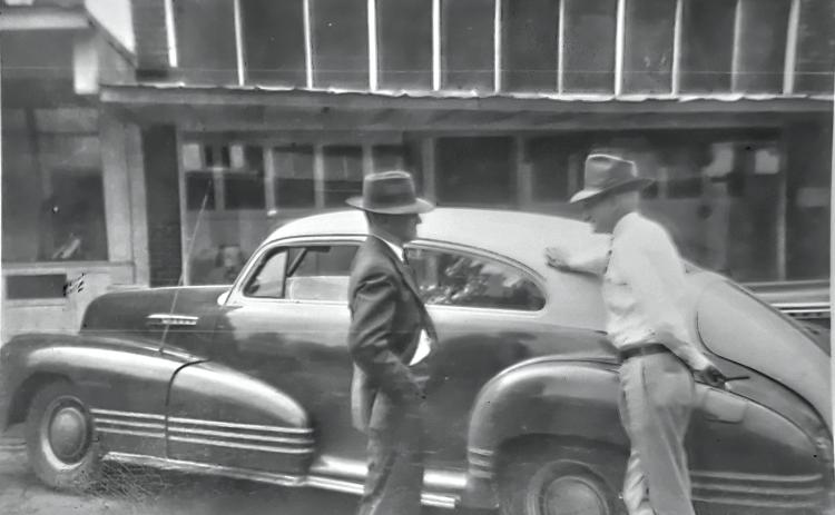 GLIMPSES  FROM  THE  PAST - This is a Rison Main Street glimpse from another time, as we see a couple of gentlemen having a discussion next to a car - possibly a late 1940's Chevrolet Fleetline, or possibly a Pontiac Torpedo (please, let us know if you can identify the automobile). We feel certain this photo was made in the second block, but we can't be sure about which buildings are seen in the background. The fellow at right we believe we know, evidence given away by what looks to be a cigar in his hand.