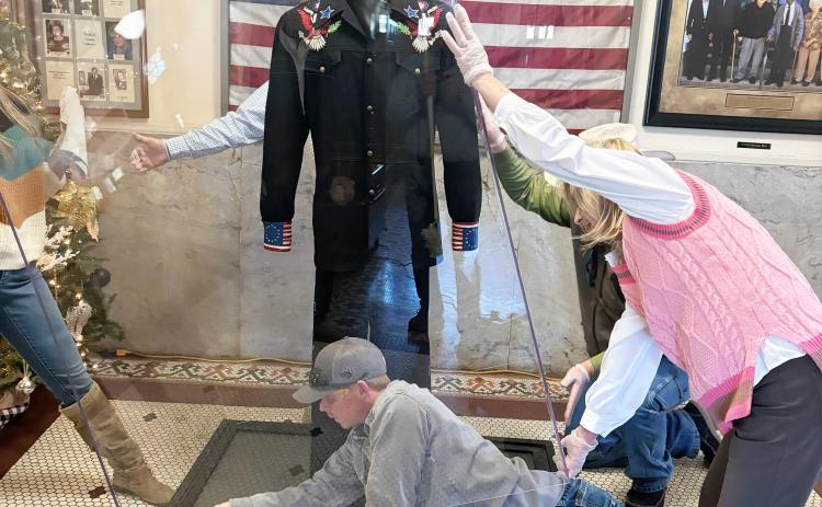 FINISHING TOUCHES ON NEW DISPLAY CASE - One of the four crew members from Watson Chapel Picture Frame installing the new display case for the suit that Johnny Cash wore during his 1976 Bicentennial Concert at the Rison High School football stadium wipes up the inside of the dust-proof case before dropping it down. After being displayed for a year at the Rock and Roll Hall of Fame in Cleveland, Ohio, and then the past few years at the Johnny Cash boyhood in Dyess, Ark., the suit is now home in its permanent.