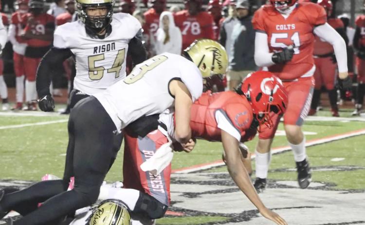 MAKING THE STOP - Rison’s Jaquis Rauls (bottom) grabs the legs of Rivercrest quarterback Cavonta Washington as teammate Eli Turner comes in to finish up the tackle in first half action of the Wildcats’ second-round playoff game at Rivercrest. Also pictured for Rison is Galvin Wilson, Jr. (no. 54 in background). (Photo by Chris Phillips)