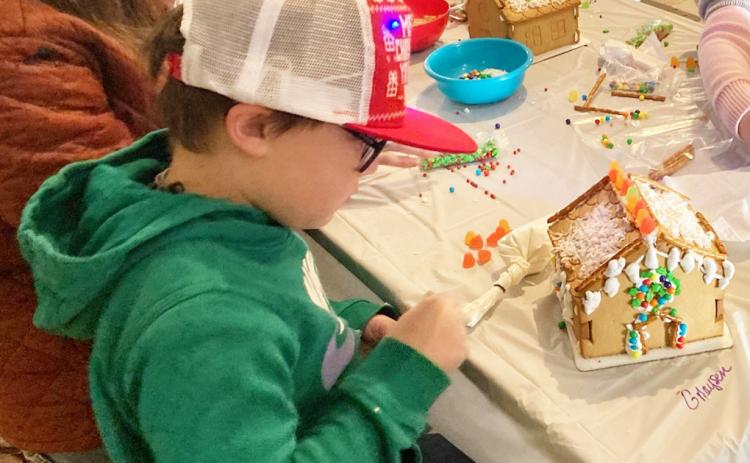 CREATING A MASTERPIECE - Greyson King intently works on his gingerbread house during The Call in Cleveland County’s Gingerbread House Workshop and Contest held Saturday during Christmas in the Village at the Pioneer Village in Rison. After completing their gingerbread houses, each house was entered in a contest sponsored by the Cleveland County Herald. King finished second in the 12 and Under division.
