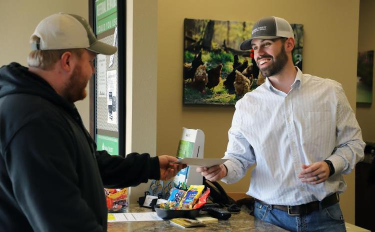 Trey Villines of the Huntsville Farm Credit branch office distributes a patronage check to a customer.