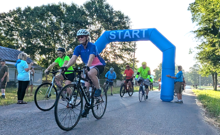 RIDERS DEPART - Riders roll out from beneath the inflatable start-finish archway set up outside the Pioneer Village at Rison for the Third Annual Cruisin’ Cleveland County bike ride held early Saturday morning. More than 20 riders from across the state took to the roads to ride routes that went as far as 65 miles. (Photo by Douglas Boultinghouse)