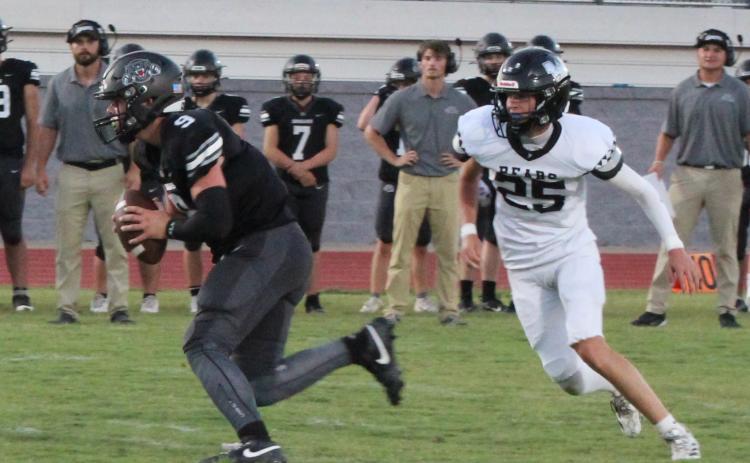 HANDFUL TO HANDLE - Woodlawn’s Brayden Jones (right, 25) pursues Izard County sophomore quarterback Kane Johnson during first half action of Friday’s non-conference game at Cougar Stadium in Brockwell. Johnson had it going through the air and one the ground as threw for 212 yards and six touchdowns while rushing 15 times for 119 yards. Johnson never left the game.