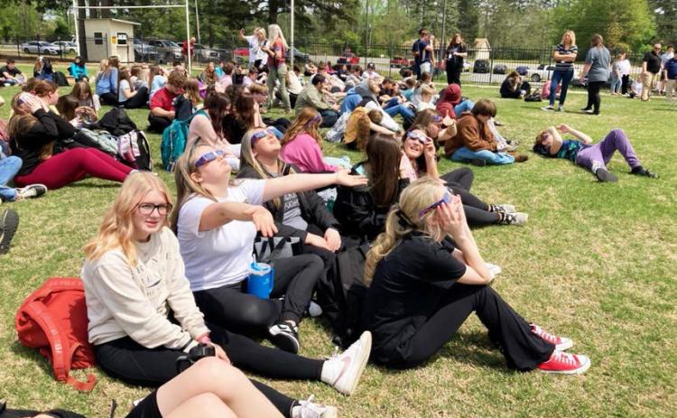 Students at Woodlawn High School kick back on the football field to take in the eclipse Monday afternoon.