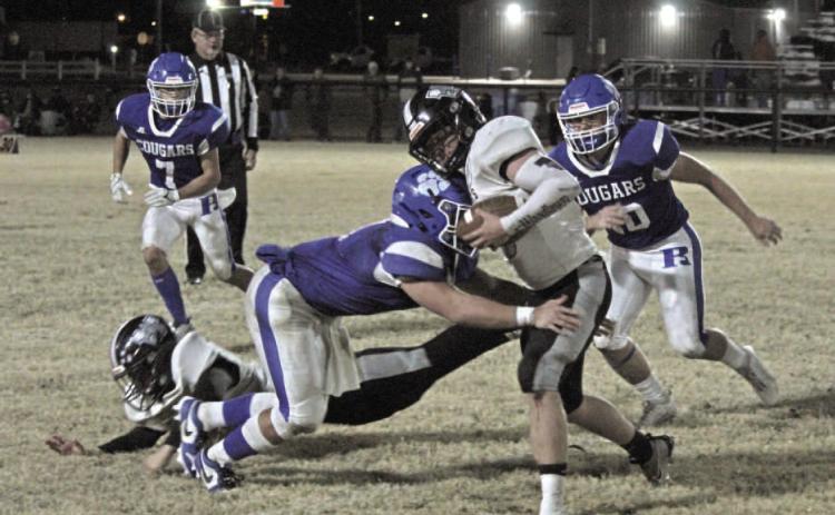 TOUGH GOING - Woodlawn junior fullback Ethan Olvier (center) tr ies to elude the tackle of Rector senior linebacker Drew Henderson during Friday night's first-round playoff game at Cougar Stadium in Rector. Henderson was part of a Cougar linebacker corps that Bears Coach Zach Meyer said is the best he has seen in two years. Once fumbles and other misques were figured in, Woodlawn finished the game with just 67 yards rushing on 36 carries, the Bears' lowest output of the season.