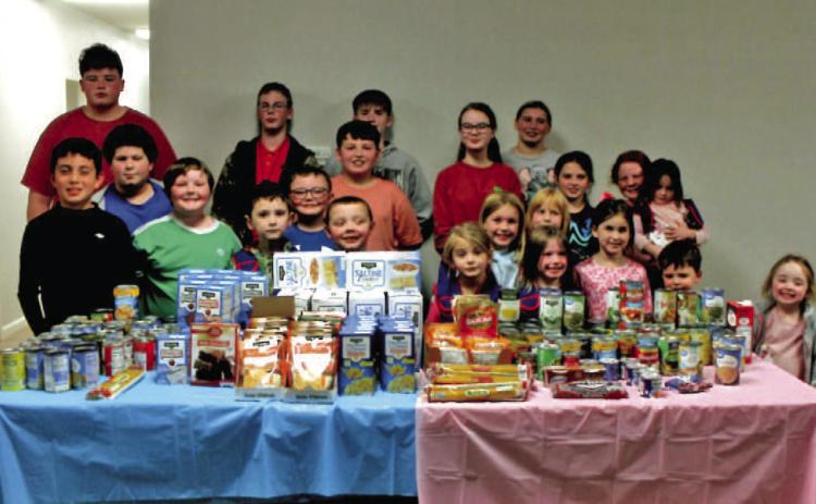 MACEDONIA MBC AWANA FOOD DRIVE - Members of the Awana program at Macedonia Missionary Baptist Church near Rison pose with the collection from their "boys versus girls" food drive held throughout the month of November. Debbie Leopard, one of the Awana leaders at Macedonia, said the food will be distributed through the church's food pantry beginning this month.