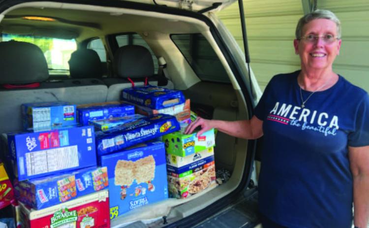 FOOD FOR STUDENTS - Donna Best, president of the Rye Extension Homemakers Club (EHC), stands next to a load of pre-packaged foods that will be going to needy students in the Woodlawn School District. The Rye EHC encourages people in the community to support this ministry that provides food for students over the weekend.